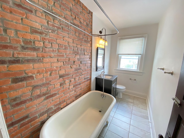 bathroom featuring a tub to relax in, tile patterned floors, brick wall, vanity, and toilet