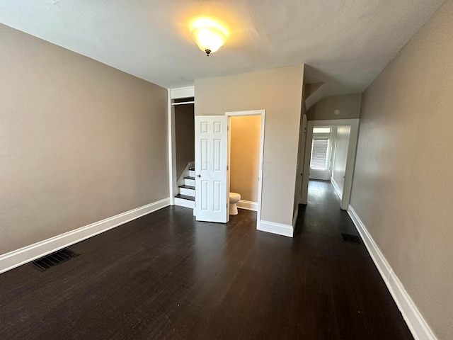 unfurnished bedroom featuring dark hardwood / wood-style floors and ensuite bath