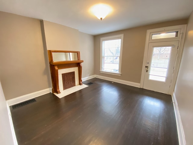 unfurnished living room with dark hardwood / wood-style flooring and a healthy amount of sunlight