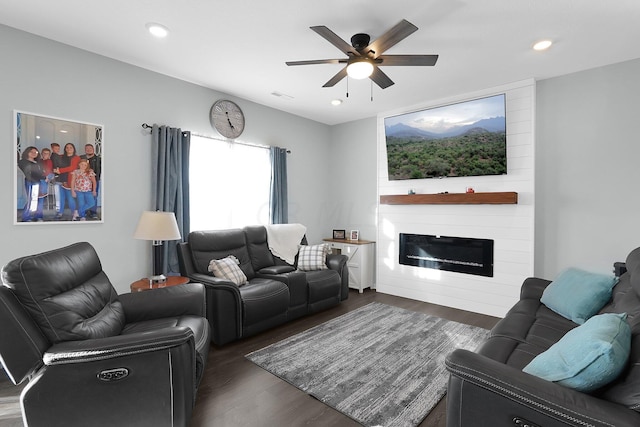 living room with a large fireplace, ceiling fan, and dark hardwood / wood-style flooring