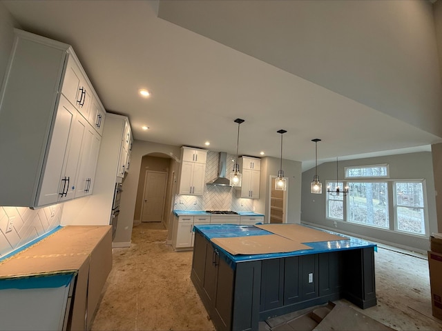 kitchen featuring tasteful backsplash, wall chimney range hood, recessed lighting, arched walkways, and white cabinetry