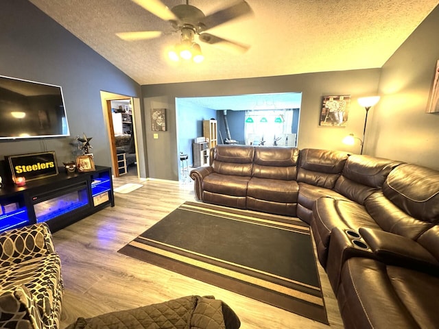 living room featuring light wood-type flooring, a textured ceiling, vaulted ceiling, and ceiling fan