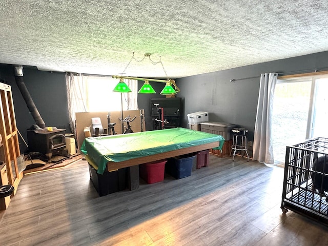 rec room featuring wood-type flooring, a textured ceiling, a wood stove, and billiards