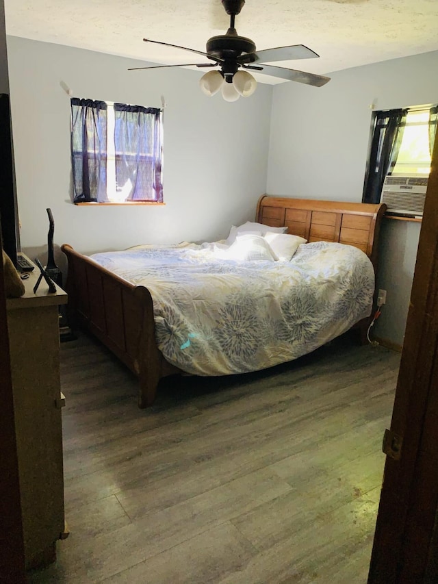 bedroom featuring ceiling fan, dark hardwood / wood-style flooring, and cooling unit