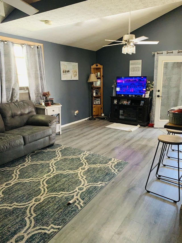 living room featuring a textured ceiling, hardwood / wood-style flooring, ceiling fan, and lofted ceiling