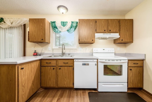 kitchen featuring white appliances, sink, a textured ceiling, light hardwood / wood-style floors, and kitchen peninsula