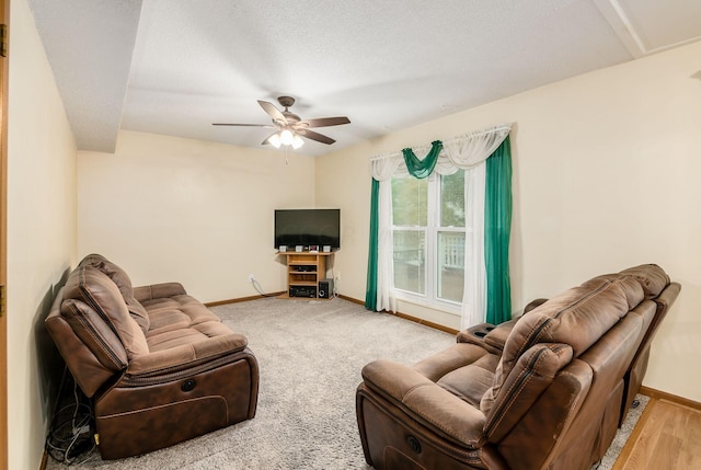 living room featuring ceiling fan, a textured ceiling, and light wood-type flooring