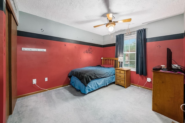 bedroom featuring a textured ceiling, light colored carpet, and ceiling fan