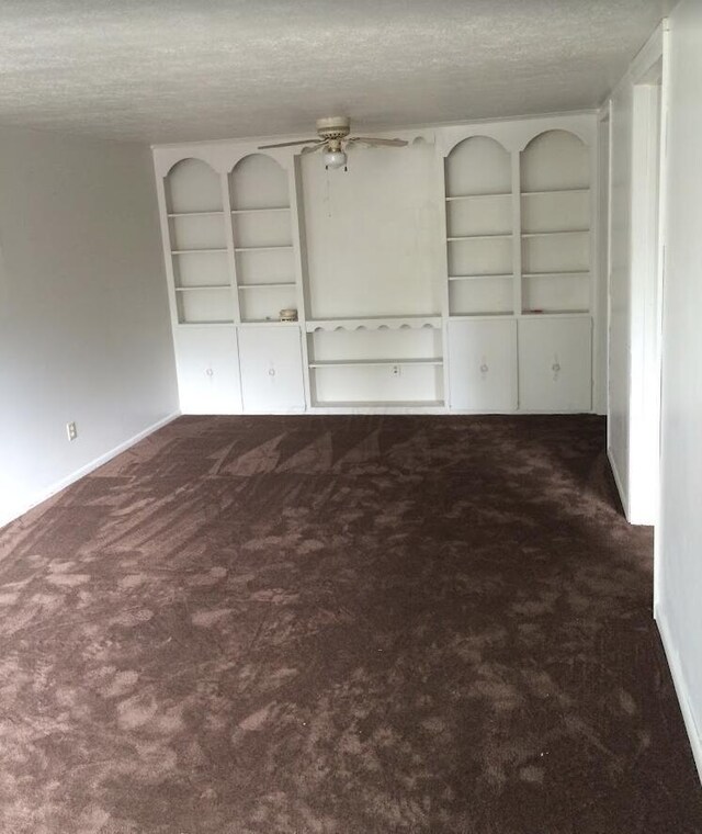 interior space featuring ceiling fan, a textured ceiling, and dark colored carpet