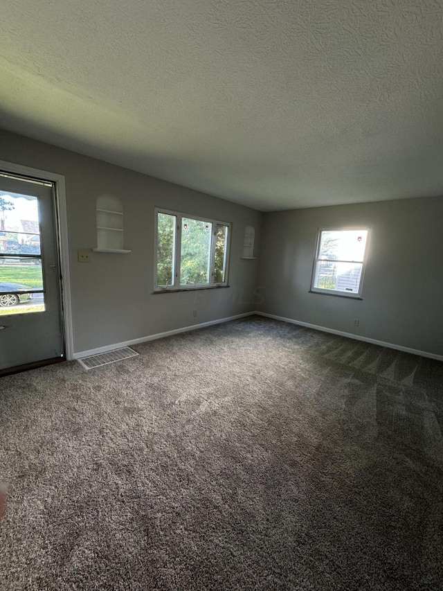 carpeted empty room featuring a textured ceiling