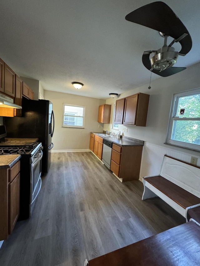 kitchen with gas range gas stove, dishwasher, ceiling fan, dark hardwood / wood-style floors, and a textured ceiling