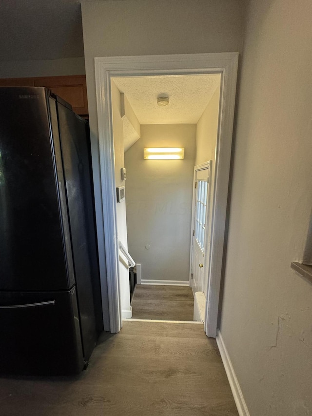 hallway with hardwood / wood-style floors and a textured ceiling