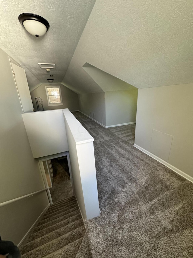 staircase with carpet floors, a textured ceiling, and vaulted ceiling