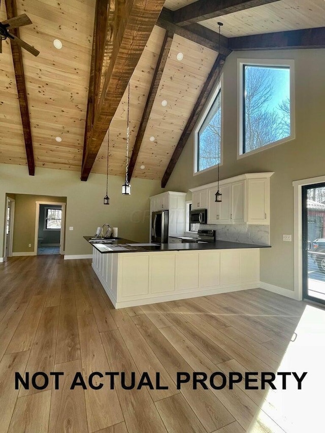 kitchen featuring white cabinetry, stainless steel appliances, beamed ceiling, pendant lighting, and light hardwood / wood-style floors