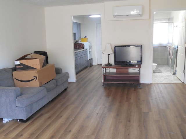 living room with a wall unit AC, washer and clothes dryer, and dark hardwood / wood-style floors