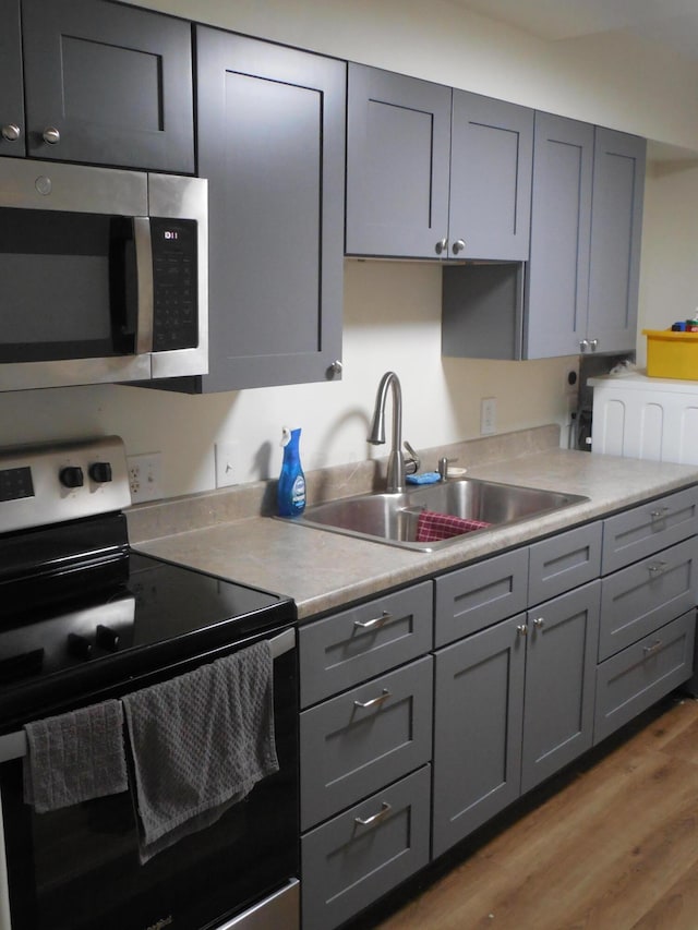 kitchen with gray cabinetry, light hardwood / wood-style flooring, stainless steel appliances, and sink