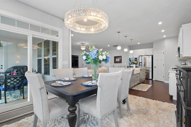 dining space featuring sink, dark wood-type flooring, and a notable chandelier