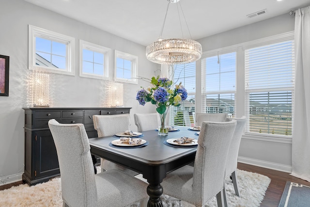 dining room with a wealth of natural light, dark hardwood / wood-style floors, and a notable chandelier