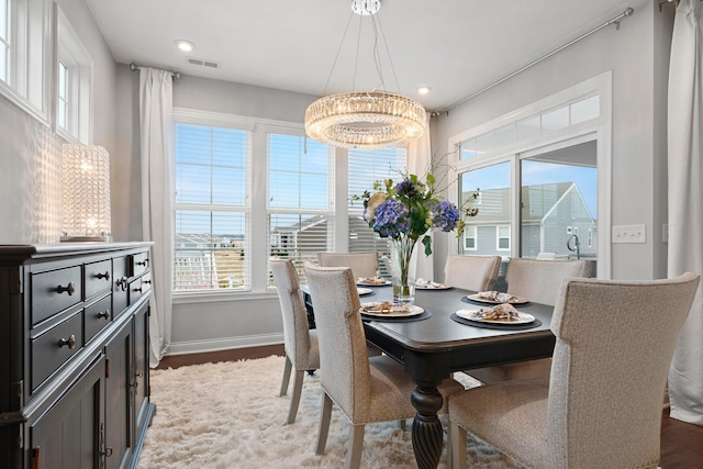 dining area featuring a wealth of natural light, dark hardwood / wood-style flooring, and an inviting chandelier