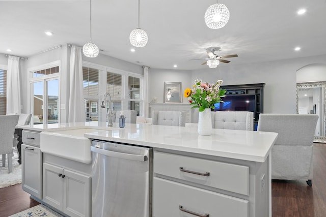 kitchen featuring dishwasher, dark wood-type flooring, a center island with sink, ceiling fan, and decorative light fixtures