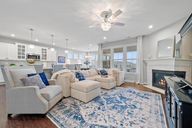 living room featuring ceiling fan, dark hardwood / wood-style flooring, and a tiled fireplace