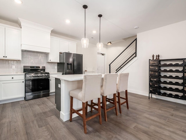 kitchen with white cabinets, stainless steel appliances, a kitchen island, and dark wood-type flooring