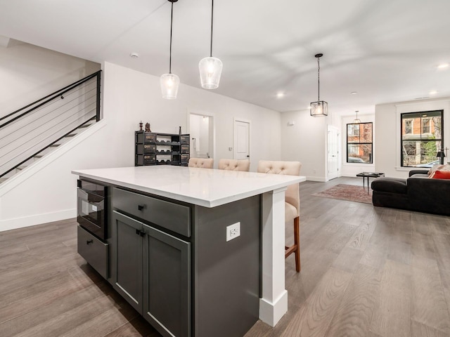 kitchen featuring hardwood / wood-style floors, decorative light fixtures, a center island, and a kitchen breakfast bar