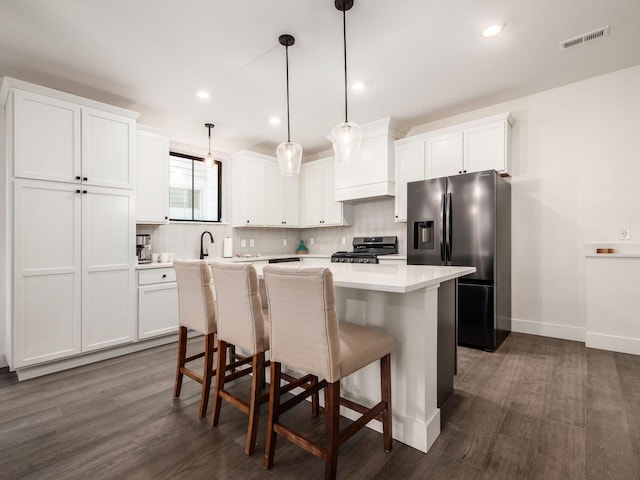 kitchen featuring appliances with stainless steel finishes, dark hardwood / wood-style flooring, decorative light fixtures, and white cabinetry