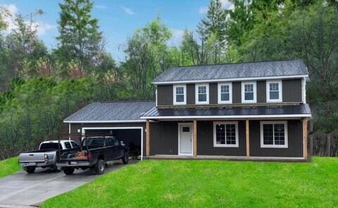 view of property featuring a front lawn, covered porch, and a garage