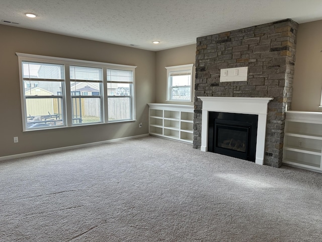 unfurnished living room featuring carpet flooring, a textured ceiling, and a large fireplace