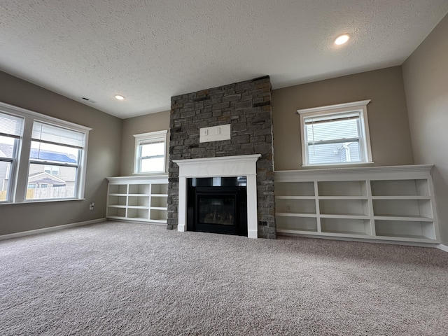 unfurnished living room with carpet flooring, a fireplace, and a textured ceiling