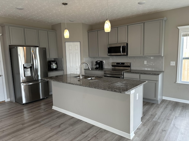 kitchen with light wood-type flooring, tasteful backsplash, a textured ceiling, stainless steel appliances, and sink