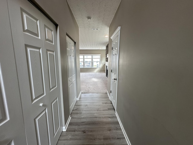 corridor featuring light hardwood / wood-style floors and a textured ceiling