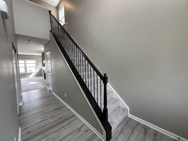 stairs featuring wood-type flooring and a towering ceiling