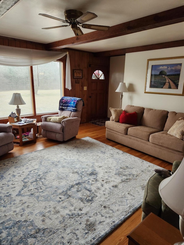 living room featuring ceiling fan, hardwood / wood-style floors, beamed ceiling, and wood walls