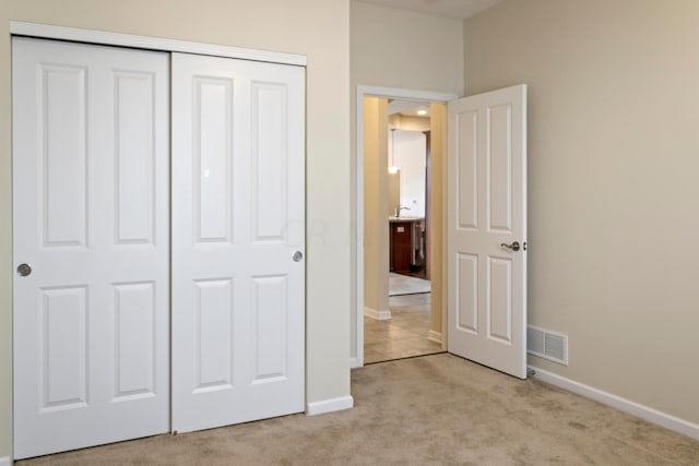 unfurnished bedroom with light colored carpet and a closet