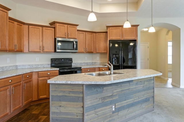 kitchen with black appliances, a center island with sink, sink, dark hardwood / wood-style floors, and decorative light fixtures