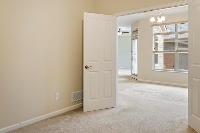 carpeted spare room with ceiling fan with notable chandelier