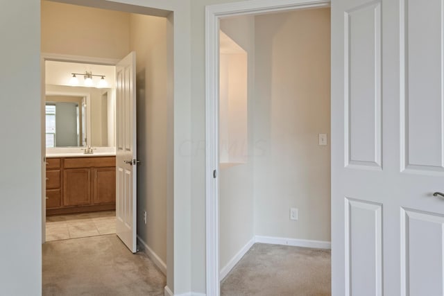 hallway featuring light carpet and sink