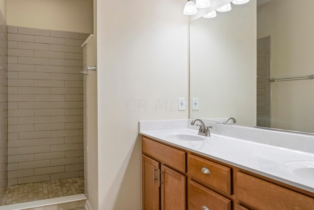 bathroom featuring a tile shower, tile patterned floors, and vanity