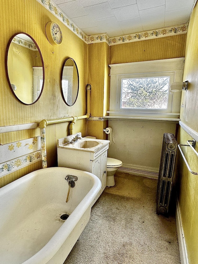 bathroom with a tub, radiator heating unit, vanity, and toilet