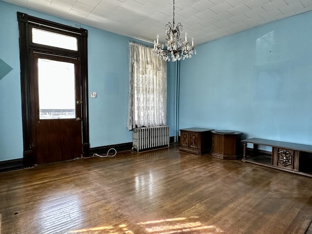 interior space featuring dark hardwood / wood-style flooring, radiator heating unit, and a chandelier