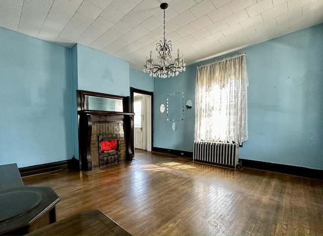 living room featuring dark hardwood / wood-style flooring, radiator, and an inviting chandelier