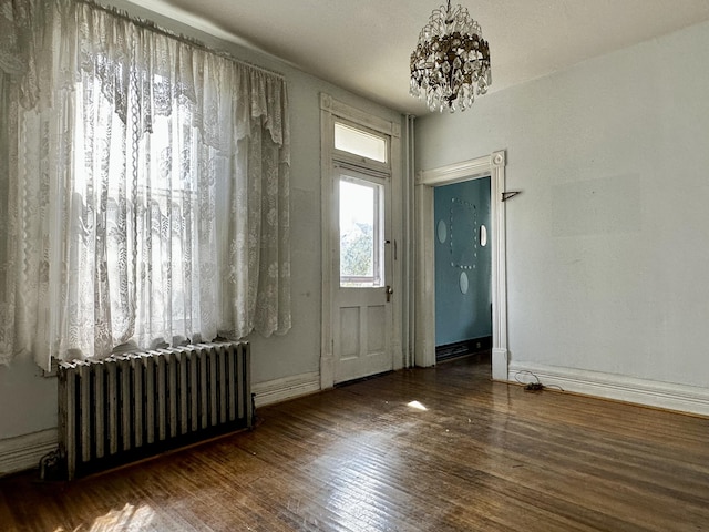 interior space featuring radiator heating unit, dark wood-type flooring, and a chandelier