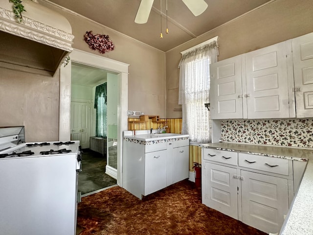 kitchen featuring backsplash, white cabinets, ventilation hood, ceiling fan, and white range with gas cooktop