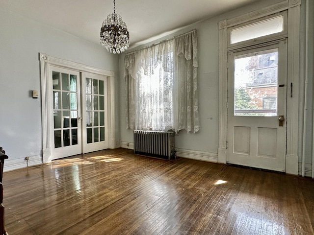 entryway with dark hardwood / wood-style floors, french doors, radiator, and a chandelier