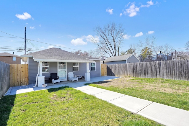 rear view of property with a shingled roof, a lawn, a patio area, and a fenced backyard