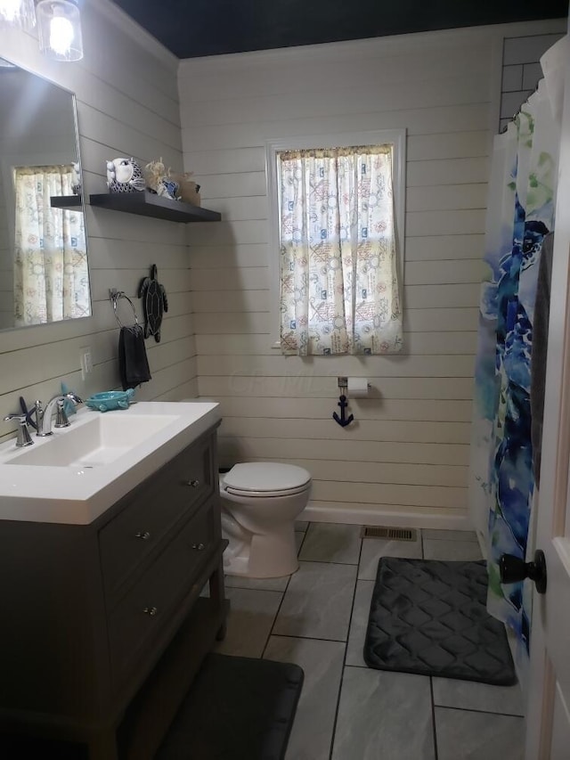 bathroom with tile patterned flooring, vanity, toilet, and wooden walls