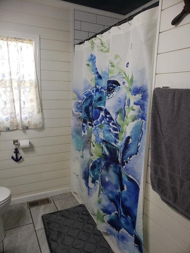 bathroom featuring wood walls, tile patterned flooring, and toilet