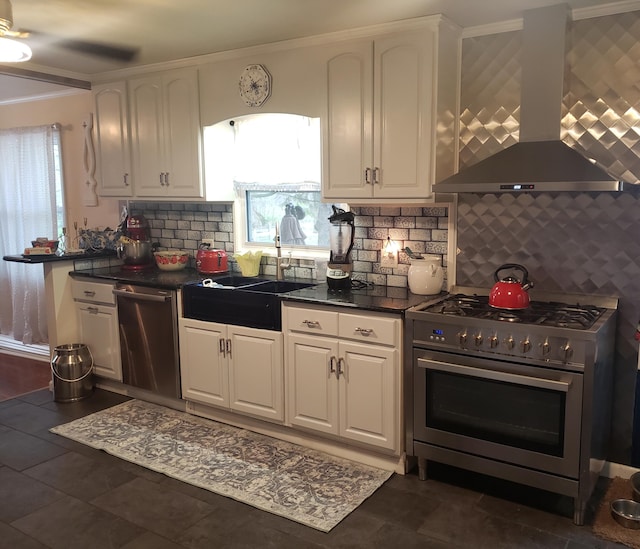 kitchen with white cabinets, stainless steel appliances, a healthy amount of sunlight, and wall chimney range hood